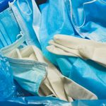 Medical trash. Coronavirus protection equipment in medical waste bin. Used face masks and sterile gloves. Doctor uniform for patient treatment in hospital. Prevention the spread of COVID-19.